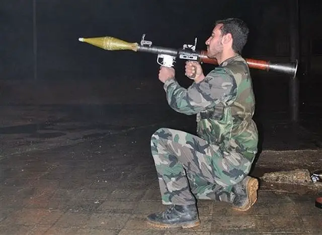 A Syrian army defector, takes his position as he holds his launcher of a rocket-propelled grenade, or RPG during a patrol in Homs province, central Syria, on Wednesday Jan. 25, 2012. 