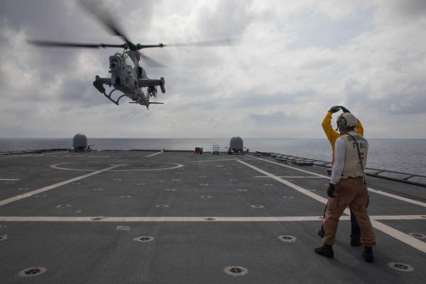 U.S. Navy sailors signal to a Marine Corps AH-1Z Viper attack helicopter from Marine Light Attack Helicopter Squadron 367 as it takes off from the flight deck of USS Canberra (LCS 30) during Navy-Marine Corps integration operations in the Philippine Sea on October 1, 2026.