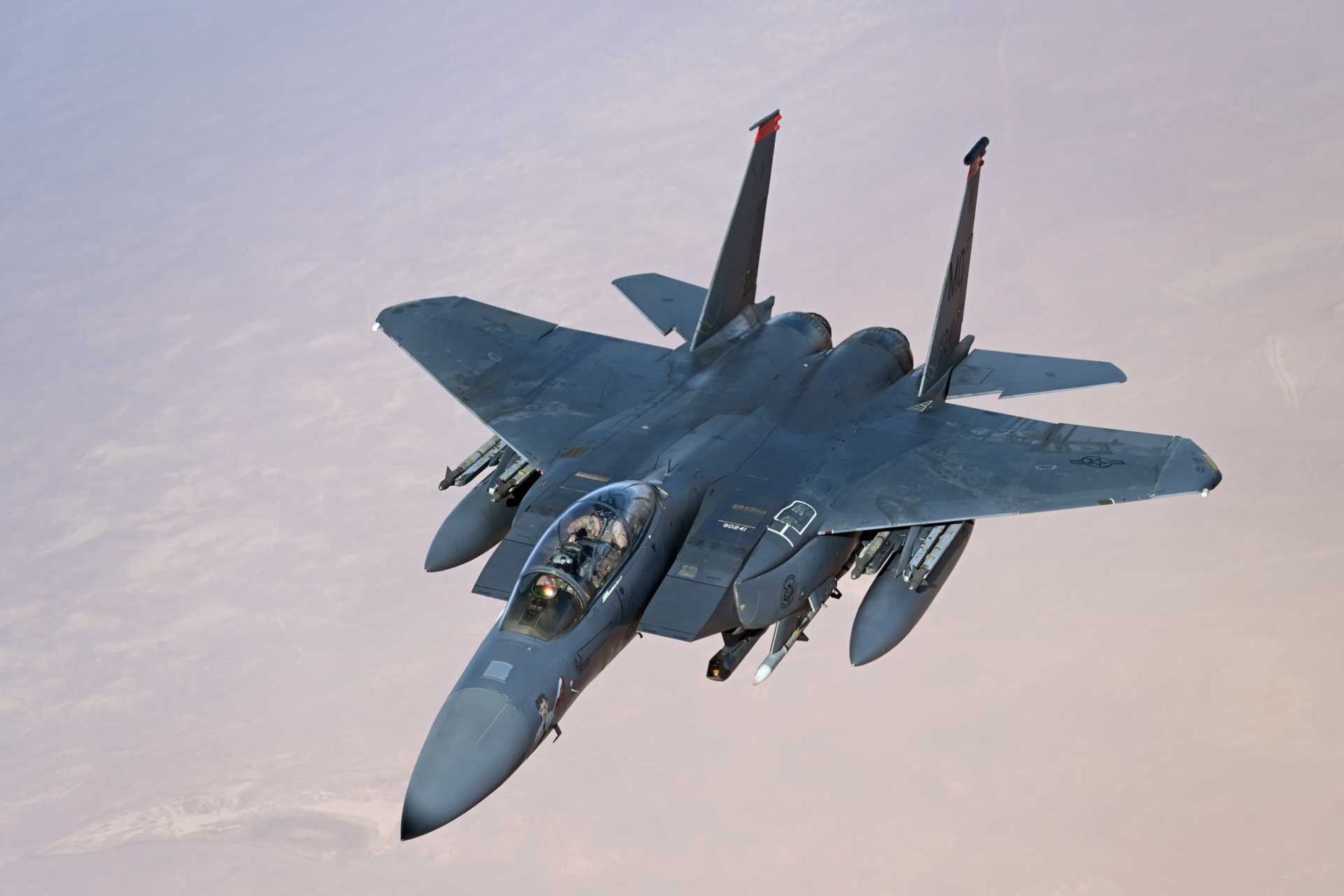 A U.S. Air Force F-15E Strike Eagle conducts a combat air patrol over the U.S. Central Command area of responsibility. The aircraft supports regional deterrence and air-defense missions and has taken on an expanded counter-drone role, including the use of APKWS II guided rockets against unmanned aerial threats.