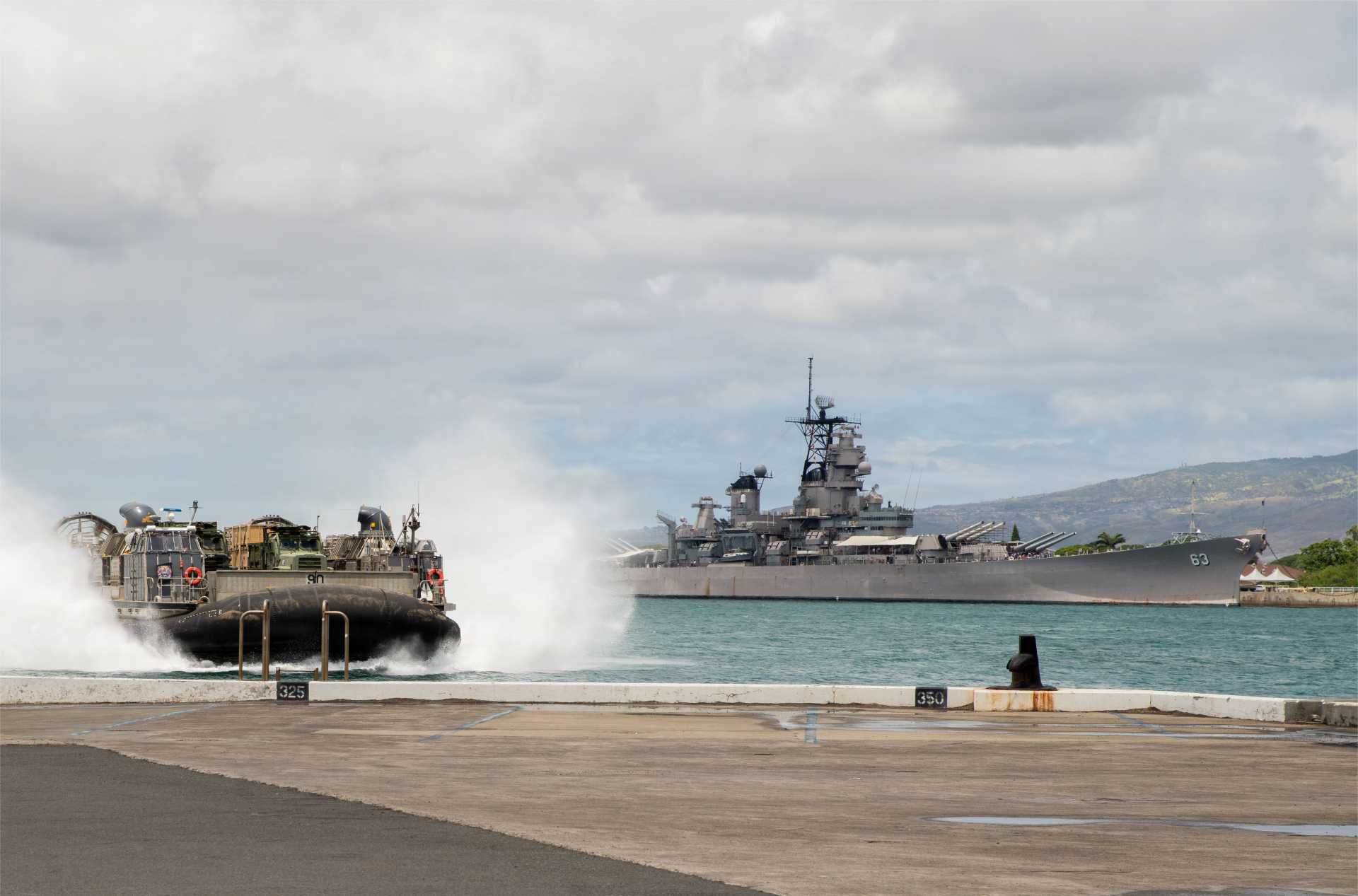 U.S. Navy Landing Craft, Air Cushion (LCAC) 90, assigned to Assault Craft Unit 5, passes the USS Missouri before entering the well deck of the Wasp-class amphibious assault ship USS Essex (LHD 2) at Joint Base Pearl Harbor-Hickam, Hawaii, on August 2, 2026.