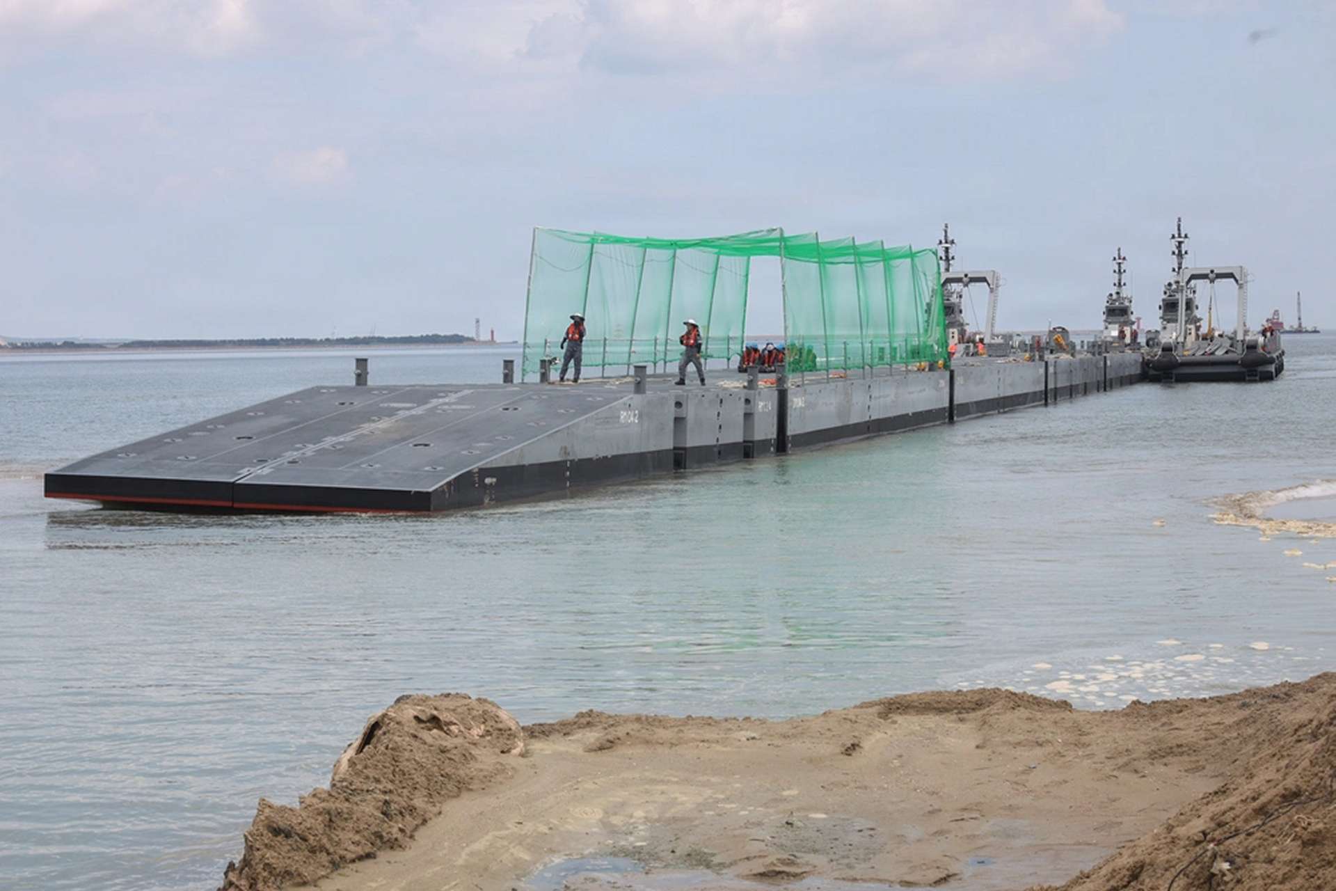 Republic of Korea personnel operate an Improved Navy Lighterage System during CJLOTS 26 at Dogu Beach on July 9, 2026. The causeway ferry carried U.S. Marine Corps vehicles ashore without fixed port infrastructure and featured overhead netting intended to reduce exposure to small drones (Picture source: U.S. DoW).