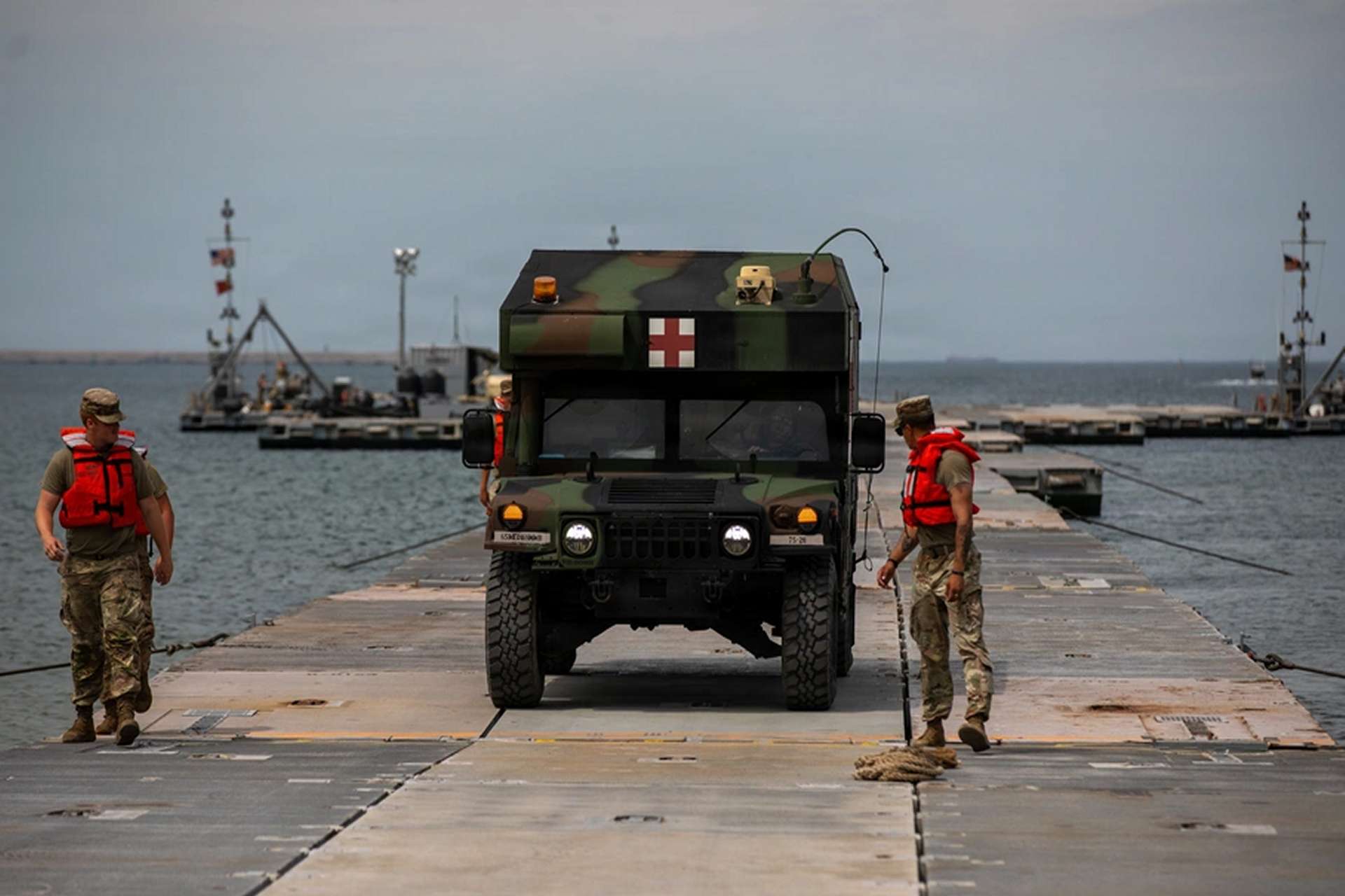 U.S. Army personnel guide an M997A3 Humvee ambulance across a temporary Trident Pier at Pohang Port during CJLOTS 2026, testing casualty evacuation through an improvised ship-to-shore logistics route (Picture source: U.S. DoW).