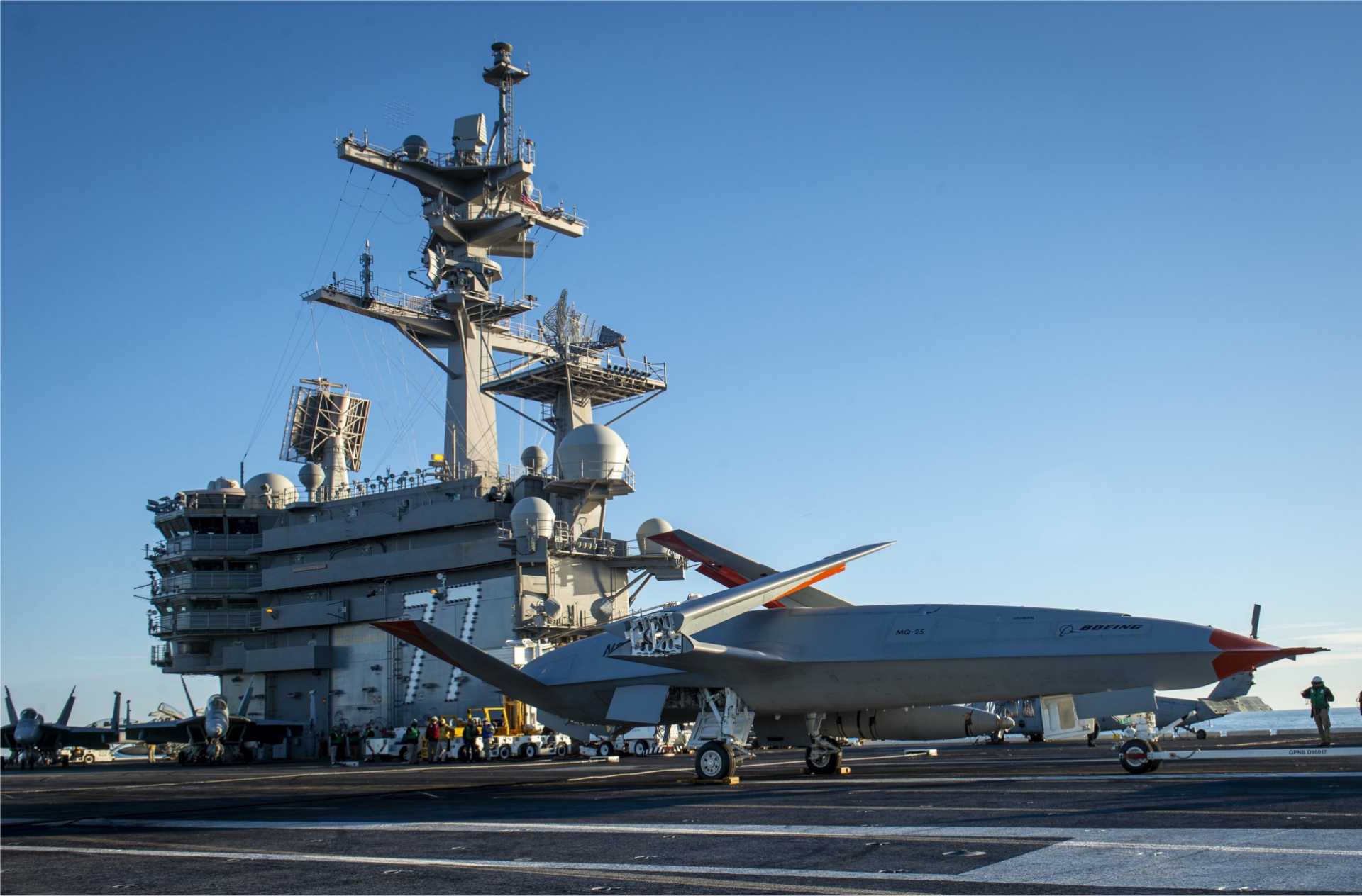 Boeing’s MQ-25 T1 unmanned test aircraft receives deck-handling commands aboard the U.S. Navy aircraft carrier USS George H.W. Bush (CVN-77) during trials supporting the development of the MQ-25A Stingray aerial refueler. (Picture source: U.S. Department of War/Defense)