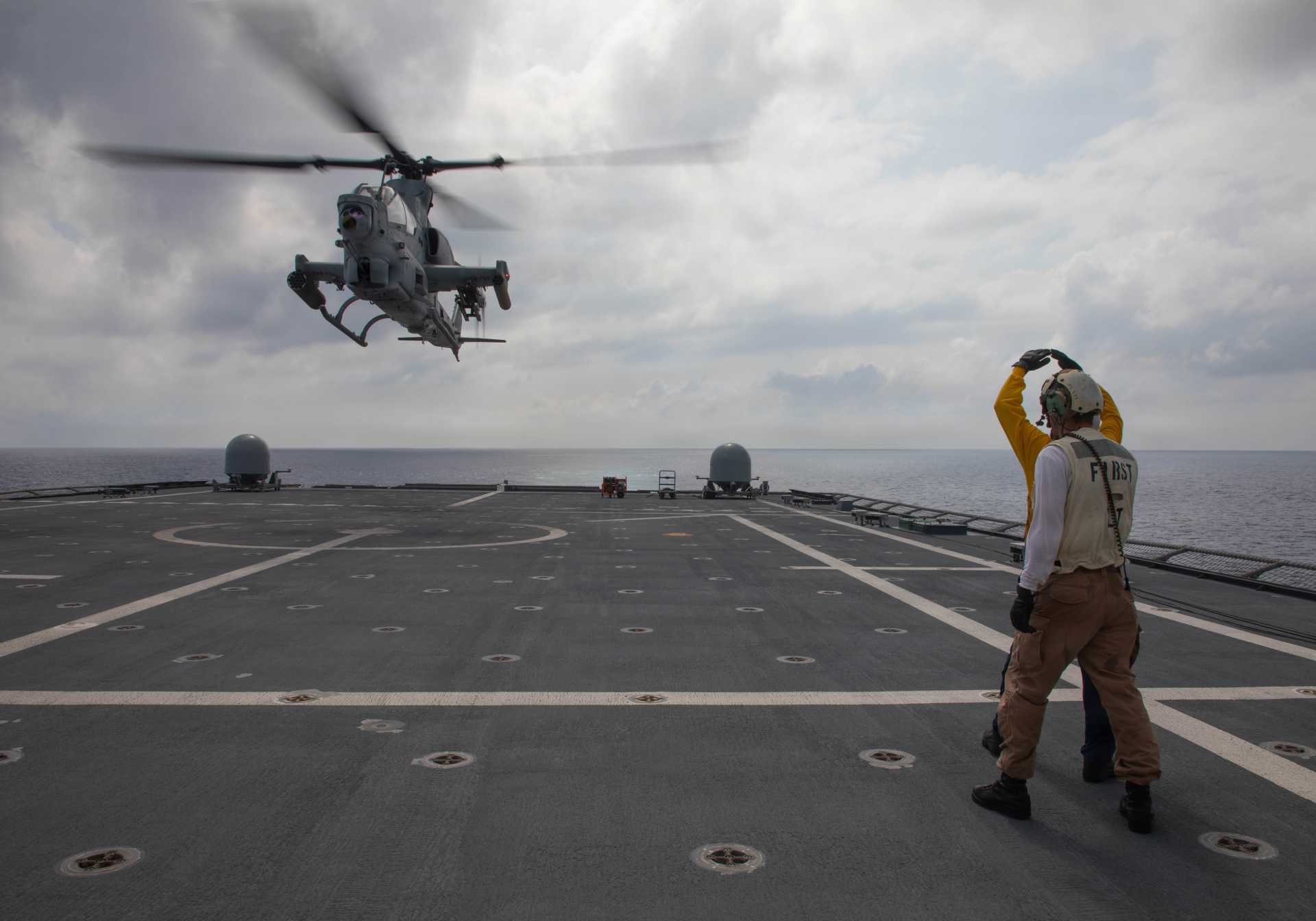 U.S. Navy sailors signal to a Marine Corps AH-1Z Viper attack helicopter from Marine Light Attack Helicopter Squadron 367 as it takes off from the flight deck of USS Canberra (LCS 30) during Navy-Marine Corps integration operations in the Philippine Sea on October 1, 2026.