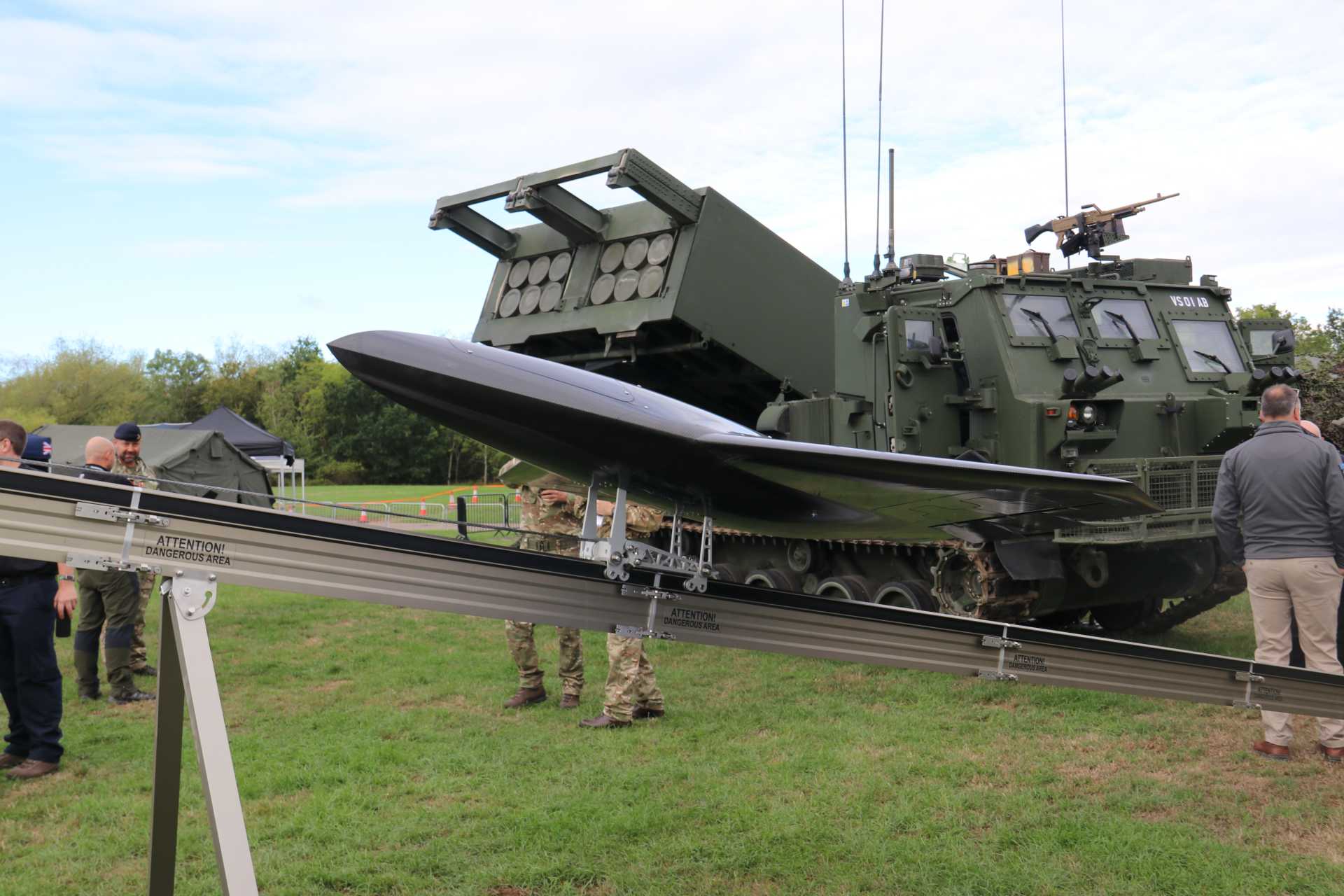The jet-powered Nyan drone is displayed in front of a British Army M270A2 Multiple Launch Rocket System at DVD 2026, highlighting the growing integration of one-way attack drones with long-range artillery units to expand deep-strike options.