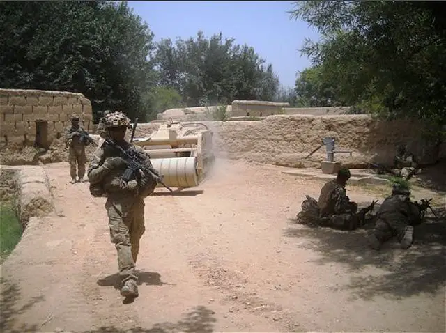 Soldiers patrol a village in Zharay district, Kandahar province, Afghanistan, alongside a remote-controlled mine clearing vehicle called the Doking. (U.S. Army picture)