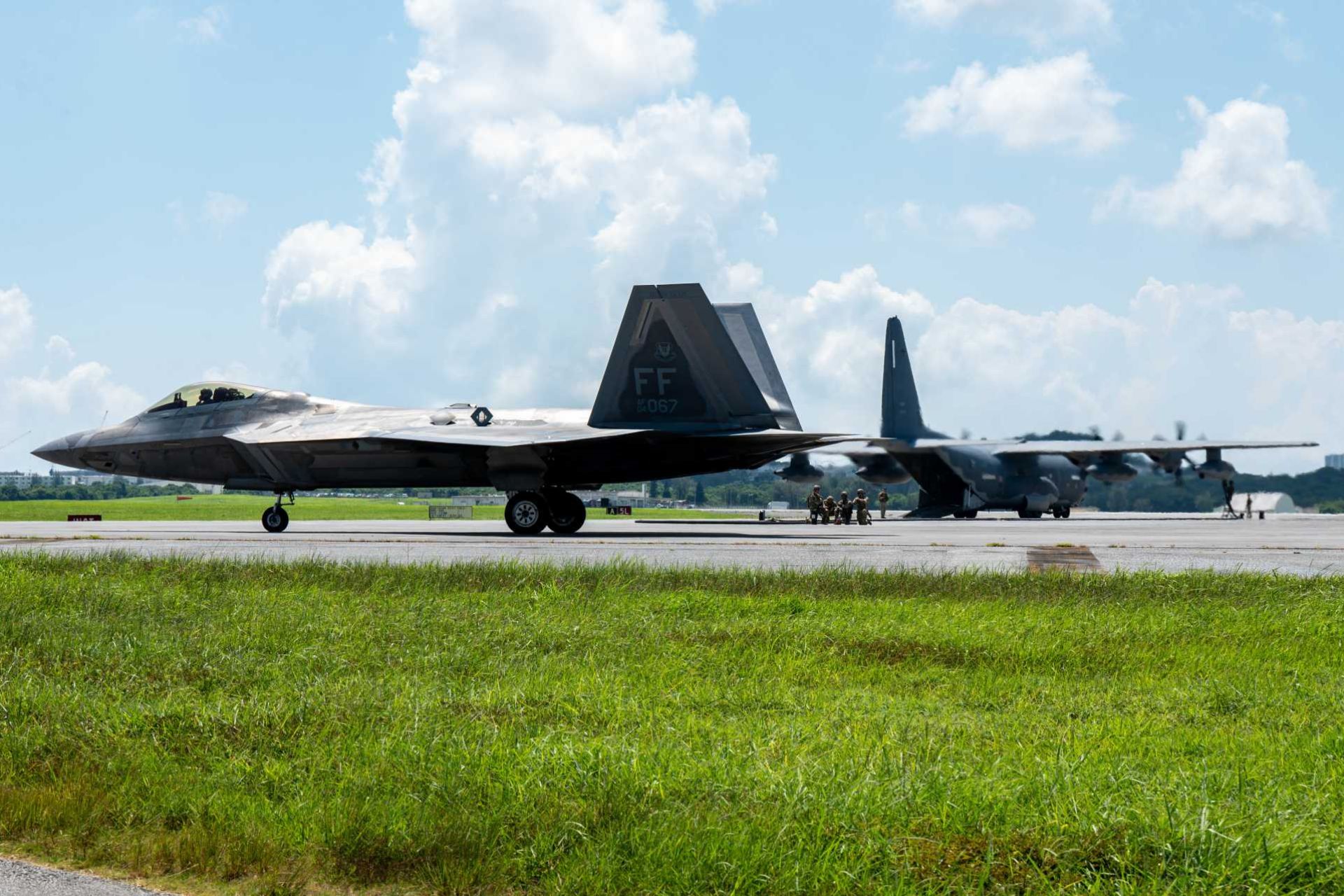 A U.S. Air Force F-22 Raptor assigned to the 27th Expeditionary Fighter Squadron taxis after completing a forward arming and refueling point operation during Beverly Beach 26-1 at Kadena Air Base, Japan, Aug. 4, 2026. Nearby, an MC-130J Commando II is refueled by Airmen from the 18th Logistics Readiness Squadron, demonstrating how dispersed fuel support can sustain rapid fighter regeneration during a regional contingency.