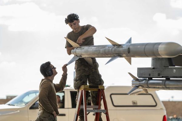 U.S. Air Force Tech. Sgt. Jordon Gonzales and Airman 1st Class Lukas Pollock, aircraft armament systems specialists with the Ohio National Guard’s 180th Fighter Wing, prepare the fins of an AIM-120 AMRAAM air-to-air missile mounted on an F-16 Fighting Falcon before a training flight in Swanton, Ohio, on September 29, 2026. (Picture source: U.S. Department of War/Defense)