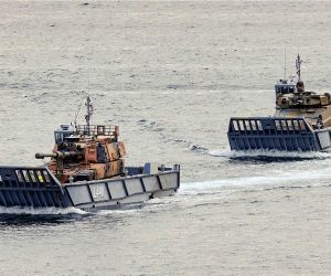 An Australian Army AS9 Huntsman 155 mm self-propelled howitzer and AS21 Redback infantry fighting vehicle are transported aboard Royal Australian Navy LCM-1E landing craft during maritime deployment trials at Garden Island in Sydney Harbour, validating their ability to support amphibious and littoral operations in the Indo-Pacific.