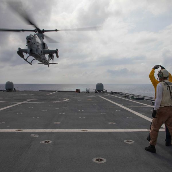 U.S. Navy sailors signal to a Marine Corps AH-1Z Viper attack helicopter from Marine Light Attack Helicopter Squadron 367 as it takes off from the flight deck of USS Canberra (LCS 30) during Navy-Marine Corps integration operations in the Philippine Sea on October 1, 2026.