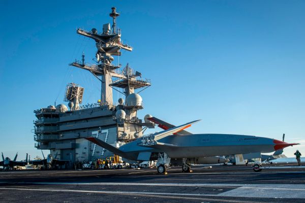A Boeing unmanned MQ-25 aircraft is given operating directions on the flight deck aboard the aircraft carrier USS George H.W. Bush (Picture source: US DoD)