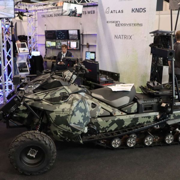 Eiselin Landsystems’ SAND-X Dual Operating Vehicle (DOV) combines high-mobility wheel-and-track performance with “optionally manned” operation, allowing troops to drive it forward and then switch to unmanned mode for last-mile resupply, casualty evacuation, or mission payload delivery in drone- and fire-threatened areas (Picture source: Army Recognition Group).