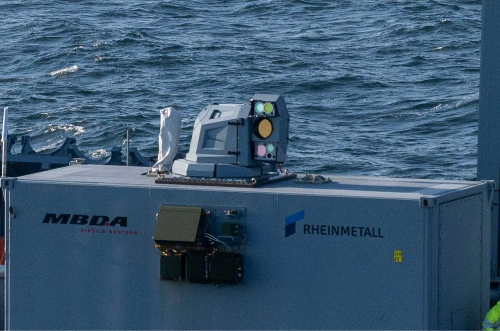 German Navy frigate FGS Sachsen conducts sea trials with Rheinmetall and MBDA’s high-energy laser weapon system, mounted on the forward deck in a containerized module during live-fire testing in maritime conditions.