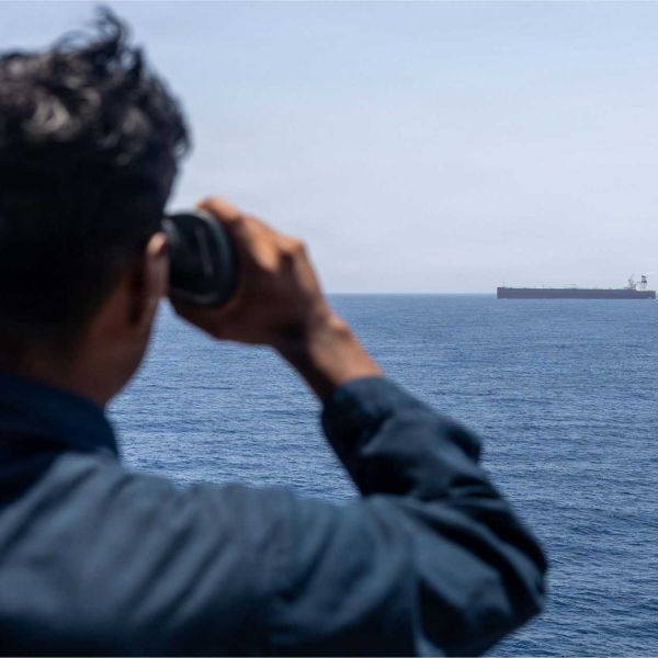 A U.S. Sailor aboard USS Rafael Peralta (DDG 115) monitors a commercial vessel during Arabian Sea patrols supporting enforcement of the U.S. maritime blockade against Iran. As of June 3, CENTCOM forces had redirected 125 commercial vessels and disabled six others to compel compliance.