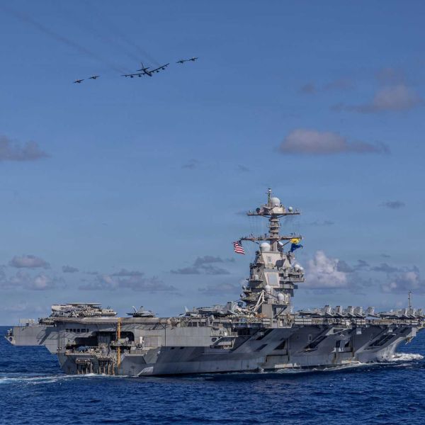 Carrier Air Wing 8 F/A-18E Super Hornets and a U.S. Air Force B-52H Stratofortress fly over the Ford-class aircraft carrier USS Gerald R. Ford (CVN 78) during operations in the western Atlantic Ocean, illustrating the expanding U.S. Navy focus on high-intensity Indo-Pacific war preparation, long-range maritime strike capability, and integrated joint-force deterrence against growing Chinese military power.