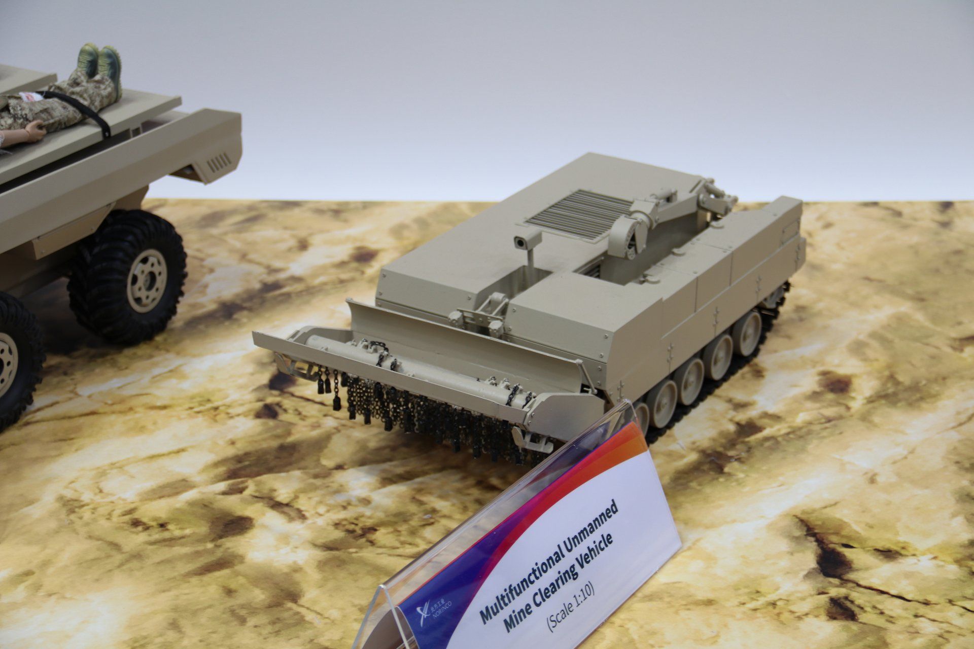 Scale model of the new Multifunctional Unmanned Mine Clearing Vehicle displayed at the NORINCO booth during UMEX 2026, showcasing China’s latest tracked UGV concept equipped for autonomous demining and obstacle clearance missions.