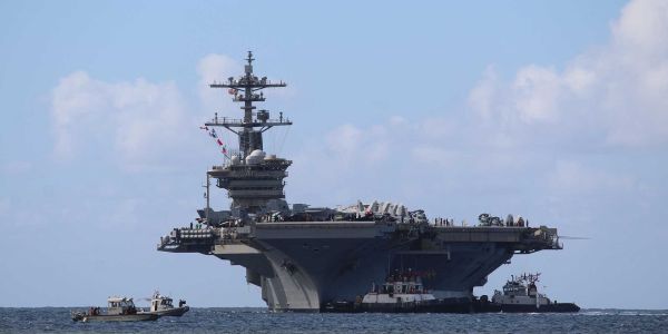 Harbor tugboats assist U.S. Navy Nimitz-class aircraft carrier USS Abraham Lincoln (CVN 72) as it arrives at Naval Base Guam for a scheduled port visit on December 11, 2025.