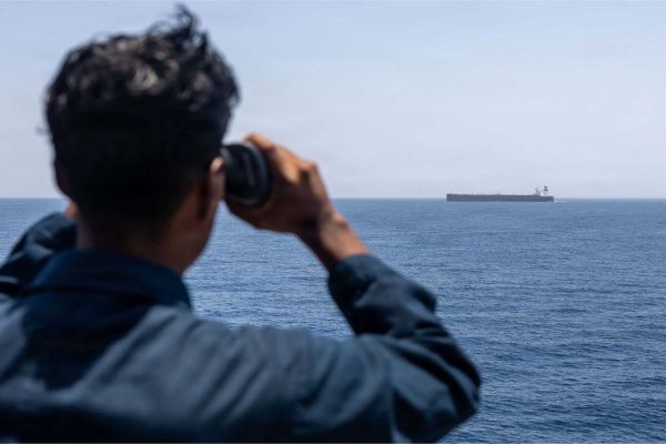 A U.S. Sailor aboard USS Rafael Peralta (DDG 115) monitors a commercial vessel during Arabian Sea patrols supporting enforcement of the U.S. maritime blockade against Iran. As of June 3, CENTCOM forces had redirected 125 commercial vessels and disabled six others to compel compliance.