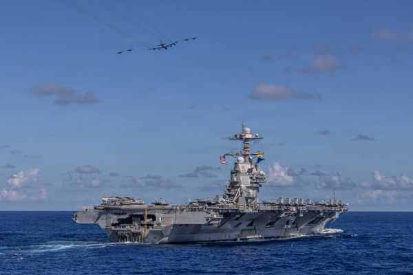Carrier Air Wing 8 F/A-18E Super Hornets and a U.S. Air Force B-52H Stratofortress fly over the Ford-class aircraft carrier USS Gerald R. Ford (CVN 78) during operations in the western Atlantic Ocean, illustrating the expanding U.S. Navy focus on high-intensity Indo-Pacific war preparation, long-range maritime strike capability, and integrated joint-force deterrence against growing Chinese military power.